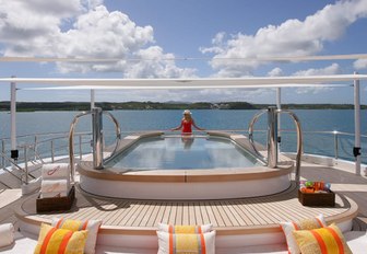 5 metre pool onboard yacht charter AMARYLLIS, female charter guest taking in the view, with sunloungers in foreground.