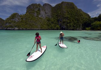 two people paddle board in the crystal clear waters of Raja Ampat