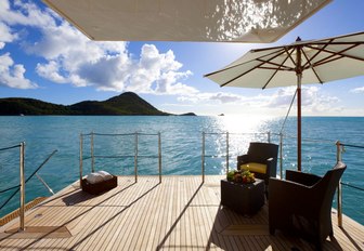 table, chairs and umbrella set up on swim platform of charter yacht ROMA