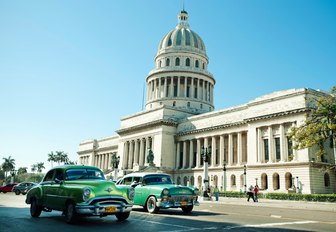 vintage cars drive past the Capitol building in Havana, the capital of Havana