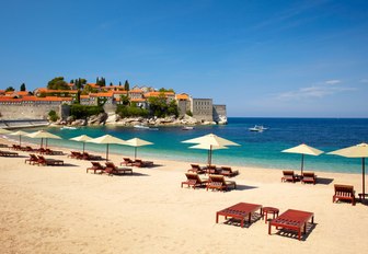 canvas chairs and loungers line up on white sand beach in Montenegro 