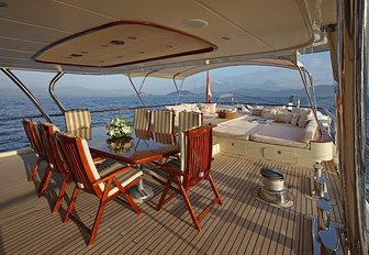 covered alfresco dining area with sunpads beyond on the aft deck of superyacht DAIMA 