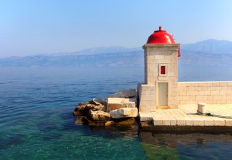 Small church with scarlet dome overlooking the clear water in Croatia