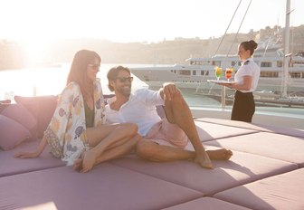 Guests reclining on foredeck sunpads of charter yacht St David