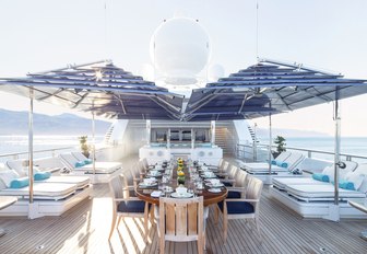 alfresco dining table with sun-loungers either side on the upper deck aft of charter yacht TITANIA