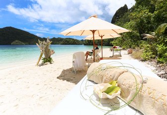 umbrellas and deck chairs line up on a deserted beach in South East Asia