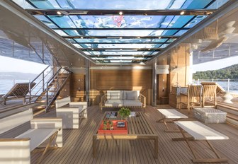 A glass encased swimming pool forms the ceiling of a superyacht beach club