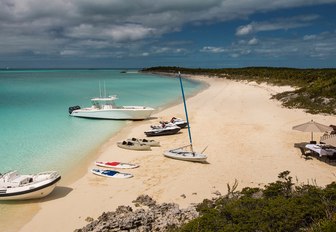 beach in the bahamas with yacht toy selection laid out on sand