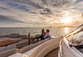 guests enjoy a glass of wine on the foredeck of luxury yacht December Six as the sun sets