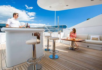 charter guests enjoys drink from the sundeck bar aboard luxury yacht DIANE 