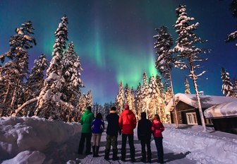 people stand below northern lights in norway