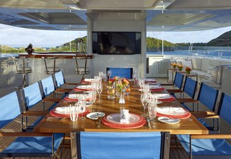 long dining arrangement on luxury yacht, with tv screens mounted on wall