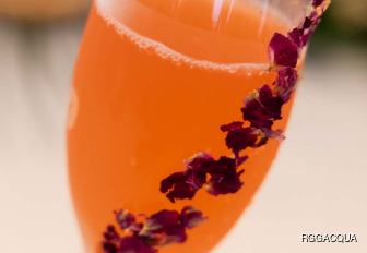 Close up of an orange colored cocktail with floral decoration