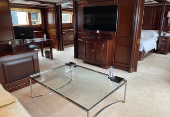 Charter yacht TELEOST master cabin lounge area with glass table and TV