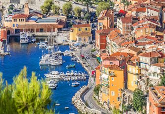 elevated view of yachts in a small habour in france with pastel buildings rising up on right