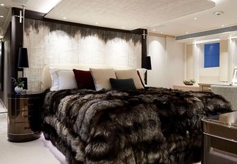 large bed with faux fur throw in the master suite aboard luxury yacht Irisha