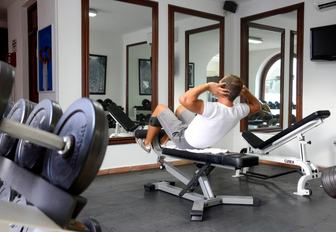 man in the gym of belmond la samanna resort doing sit ups in front of mirror