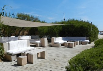 Wooden terrace with tables, comfy seating and stools at the infamous Le Club 55 in St Tropez, France