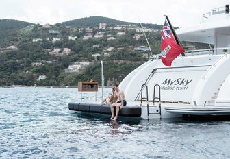 two guests sit on the edge of the swim platform on board motor yacht MYSKY