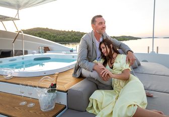 charter guests relax next to superyacht jacuzzi