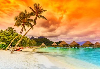 Bright sunset in Bora Bora, French Polynesia. Otemanu mountain, beach and palm trees.