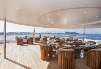 circular dining table on the shaded section of the upper deck aft aboard luxury yacht O’PTASIA  