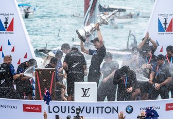 Emirates Team New Zealand celebrate with champagne on the podium after being presented with the America's Cup trophy in Bermuda