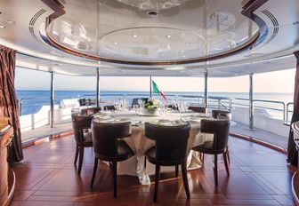 semi-alfresco dining setup with circular table on the upper deck aft of motor yacht CHECKMATE 