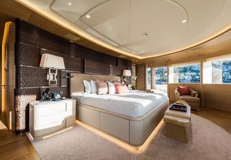 master suite with dark wood headboard and panoramic windows on board motor yacht Here Comes The Sun 