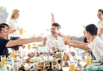 charter party toasts over breakfast on the upper deck aft of luxury yacht Ramble on Rose 