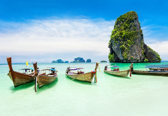 traditional Thai fishing boats line up on the white sandy shores of Maya Beach on Koh Phi Phi, Thailand