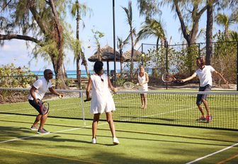 Couples playing doubles tennis on Thanda Island, Indian Ocean