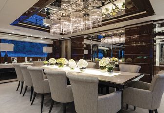 formal dining area overlooked by glittering chandelier in the main salon of charter yacht 11/11 