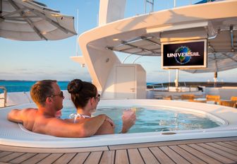 guests unwind in the Jacuzzi while watching a film on board charter yacht CHECKMATE 
