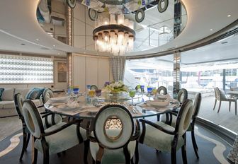 circular, glass dining table underneath stunning light fixture on board luxury yacht SCORPION