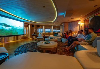 Couple sitting on sofa watching large TV screen on Superyacht SUNRAYS