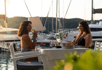 Friends chatting at waterside restaurant in Turkey overlooking the Mediterranean and yachts in the marina