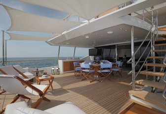 circular alfresco dining table and loungers under bimini shade on upper deck aft of motor yacht SKYLER 