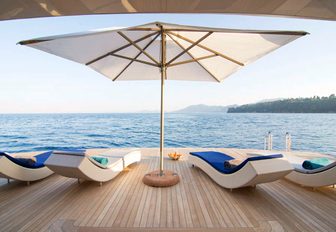 sun loungers and umbrella laid out on swim platform of luxury yacht O’PTASIA