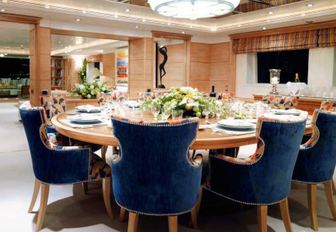 circular dining table and view velvet chairs in dining salon aboard charter yacht BALAJU 