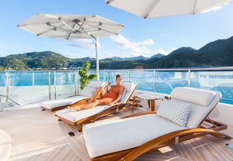 female guest unwinds on a sun lounger on the sundeck of luxury yacht ‘King Baby’ 