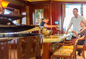 piano in foreground with guests being served drinks at the bar in the skylounge of superyacht ‘Amarula Sun’ 
