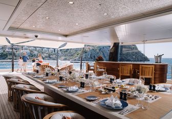 al fresco dining table and bar on the upper deck aft of luxury yacht Here Comes The Sun 