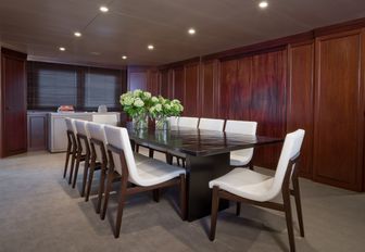 dining salon with dark wooden table and wall panels on board charter yacht CYAN
