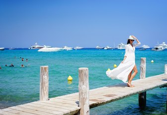 female charter guest strolls along jetty of Le Club 55, St Tropez, France