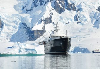 A superyacht explorer against a backdrop of a snowy peak in Antarctica