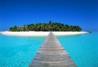 A wooden pier leading out over a turquoise sea from an island in the Philippines in Southeast Asia