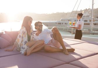 Guests reclining on foredeck sunpads of charter yacht St David