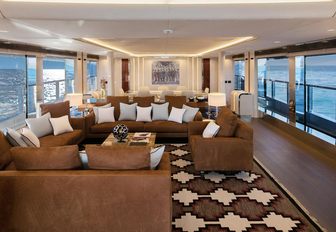 deep sofas and armchairs in brown upholstery in the main salon of charter yacht NAMASTE