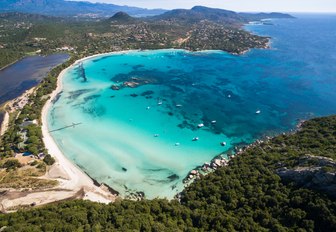 Aerial shot of bay in Corsica, with turquoise sea and white sand beach 